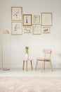 Paintings in golden frames, pink chair, table and lamp set on th Royalty Free Stock Photo