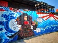 Paintings of samurai, waves, Mount Fuji and the Japanese flag on the warehouse wall.