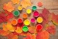 Paints, brushes, autumn leaves on wooden background. Royalty Free Stock Photo