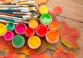 Paints, brushes, autumn leaves on wooden background. Royalty Free Stock Photo