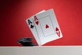 A pair of aces are balancing over the table, next to a stack of poker chips. On a red background, Royalty Free Stock Photo