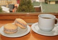 Pair of Alfajores, Traditional Latin American Sweets and a Cup of Hot Tea Served on Wooden Table by the Window, Ushuaia