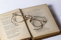 A pair of Antique Eyeglasses sitting on a opened vintage hymnal on a white background