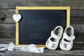 Pair of baby shoes and blank blackboard Royalty Free Stock Photo