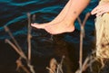 Pair of bare feet touch dark blue water Royalty Free Stock Photo