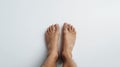 A pair of bare human feet against a white background, toes pointing upwards