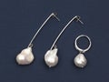 Pair of baroque pearl silver earrings with pendant on dark blue background Royalty Free Stock Photo