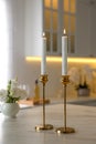 Pair of beautiful golden candlesticks on white marble table in kitchen