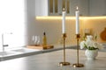 Pair of beautiful golden candlesticks on white marble table in kitchen, space for text