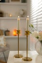 Pair of beautiful golden candlesticks on white table in room