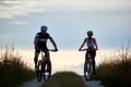 Pair of bicyclist riding bikes on country road. Fit young people in sportswear cycling downhill