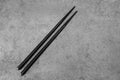 Pair of black chopsticks on concrete