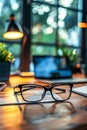 Close-Up of Black Eyeglasses on a Wooden Desk With Blurred Computer Screen in Background Royalty Free Stock Photo