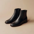 A pair of black leather ankle boots on a beige background Royalty Free Stock Photo