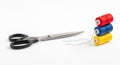 A pair of black scissors and three colorful thread spools arranged on a clean white background, representing sewing, crafting, and Royalty Free Stock Photo
