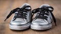 a pair of black and silver sneakers on a wooden floor with black laces on the top of the shoes and bottom of the shoes Royalty Free Stock Photo