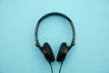 A pair of black stylish headphones with wires lie on a blue background in the middle