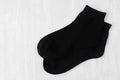 Pair blank black medium socks flat lay on white wood board, side view - mock up for design, print, presentation, advertising.