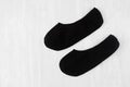 Pair blank black small, low socks flat lay on white wood board, side view - mock up for design, print, presentation, advertising.