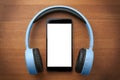 Pair of blue headphones around a blank screen smartphone on orange wooden table Royalty Free Stock Photo