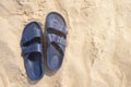 Pair of blue plastic buckled sandals or flip-flops on a beach sand with copy space Royalty Free Stock Photo