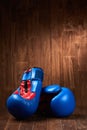 Pair of blue and red boxing gloves on wooden surface against wooden background.