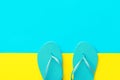 Pair of blue rubber beach slippers on duotone bright yellow cyan background. Imitation of sand and sea. Creative flat lay. Summer Royalty Free Stock Photo