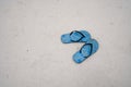 A pair of blue rubber slipper sandals on white sand beach Royalty Free Stock Photo
