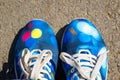 A pair of blue textile sport shoes with white laces on a background of asphalt on a sunny day. Close-up, top view