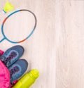 The pair of blue women`s sneakers and bottle in pink backpack,  badminton racket and shuttlecock  on white wooden surface Royalty Free Stock Photo