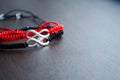 Pair bracelets in black and red with infinity. Handmade woven bracelets. Handmade decorations. Background with beads with hearts