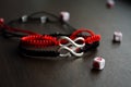 Pair bracelets in black and red with infinity. Handmade woven bracelets. Handmade decorations. Background with beads with hearts Royalty Free Stock Photo