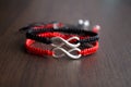 Pair bracelets in black and red with infinity. Handmade woven bracelets. Handmade decorations. Background with beads with hearts Royalty Free Stock Photo