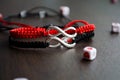 Pair bracelets in black and red with infinity. Handmade woven bracelets. Handmade decorations. Background with beads with hearts