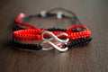 Pair bracelets in black and red with infinity. Handmade woven bracelets. Handmade decorations. Background with beads with hearts Royalty Free Stock Photo