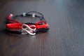 Pair bracelets in black and red with infinity. Handmade woven bracelets. Handmade decorations. Background with beads with hearts