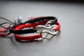 Pair bracelets in black and red with infinity. Handmade woven bracelets. Handmade decorations. Background with beads with hearts