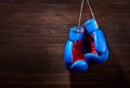 A pair of bright blue and red boxing gloves hangs against wooden background. Royalty Free Stock Photo