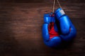 A pair of bright blue and red boxing gloves hangs against wooden background. Royalty Free Stock Photo