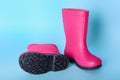 Pair of bright pink rubber boots on light blue background Royalty Free Stock Photo