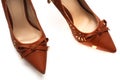 A pair of brown colored ladies high heels shoes with a bow ribbon at the front