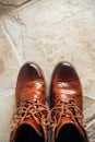 A pair of Brown natural leather medium boots with unlaced shoelaces standing on natural stone floor top view Royalty Free Stock Photo