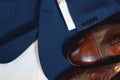 A pair of brown shoes with a white stripe on the side sit on a blue jacket Royalty Free Stock Photo