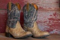 A pair of camouflage cowboy boots on red barn board Royalty Free Stock Photo