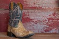 A pair of camouflage cowboy boots on red barn board