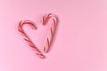 Pair of candy canes in shape of heart on pink