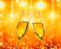 A pair of champagne flutes with golden bubbles on golden stars light background Royalty Free Stock Photo