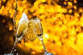 A pair of champagne flutes with golden bubbles make cheers on golden light background with space for text Royalty Free Stock Photo