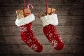 Pair of Christmas stockings filled with gifts and sweets hanging in front of a rustic wooden wall Royalty Free Stock Photo