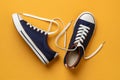 Pair of classic blue gumshoes or sneakers with white shoe laces on a textured yellow background. Comfortable shoes for fitness and Royalty Free Stock Photo